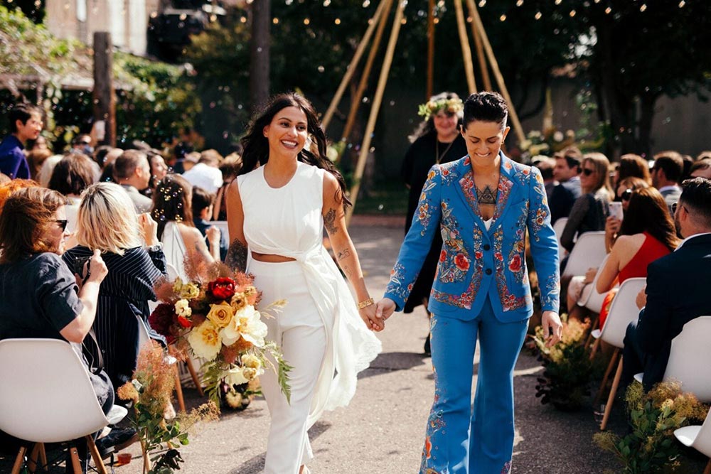 boho wedding ceremony with two brides in bridal suits